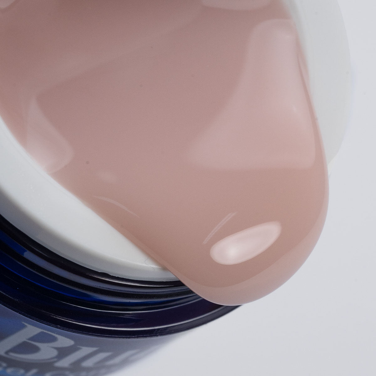 close no pote de gel construtor universal nude, de cor rosada. o pote está virado, dando o efeito cascata